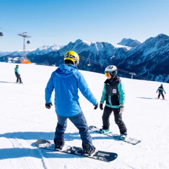 Snowboardlehrer fährt mit Schüler Snowboard 
